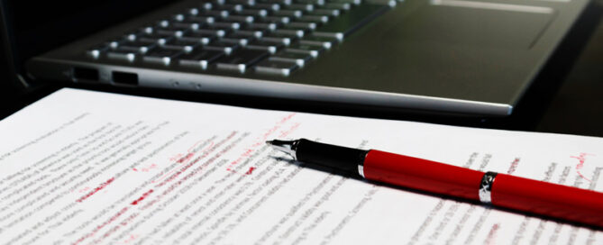 Lektorat und Korrektorat: Der Feinschliff, der den Unterschied macht | Ein roter Kugelschreiber liegt auf dem rot lektoriertem Manusscript