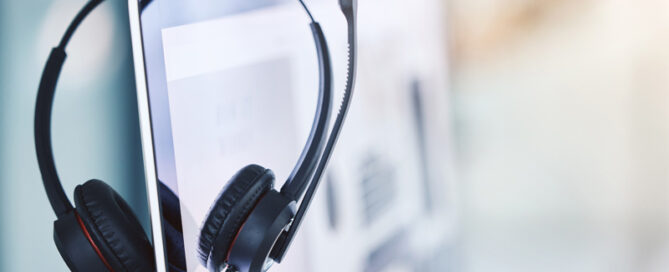 Gedolmetscht oder übersetzt – g’hupft wie g’hatscht? | Headset hängt über der Kante des Bildschirms