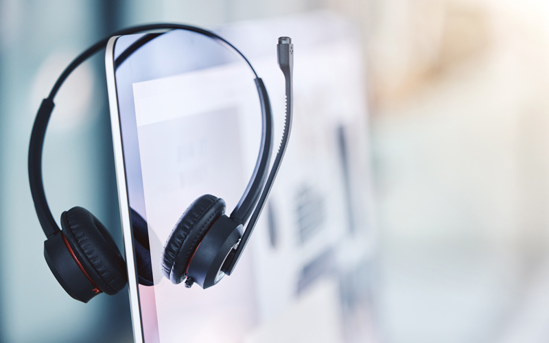 Gedolmetscht oder übersetzt – g’hupft wie g’hatscht? | Headset hängt über der Kante des Bildschirms