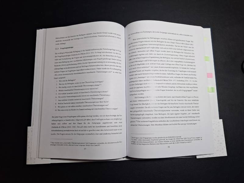 Eine aufgeschlagene Masterarbeit liegt auf einem schwarzen Tisch.